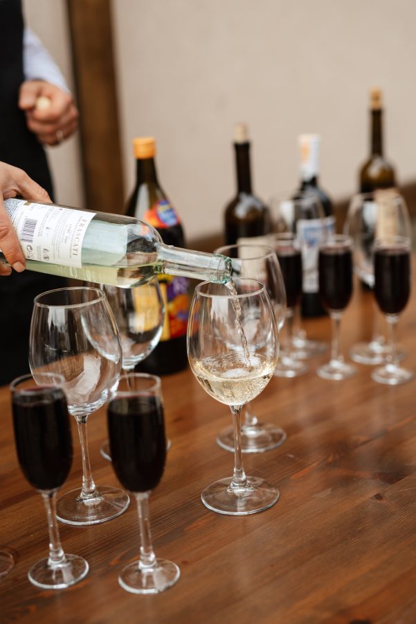 Inschenken van witte wijn met glazen rode wijn eromheen op tafel voor wijnproeverij in Overijssel